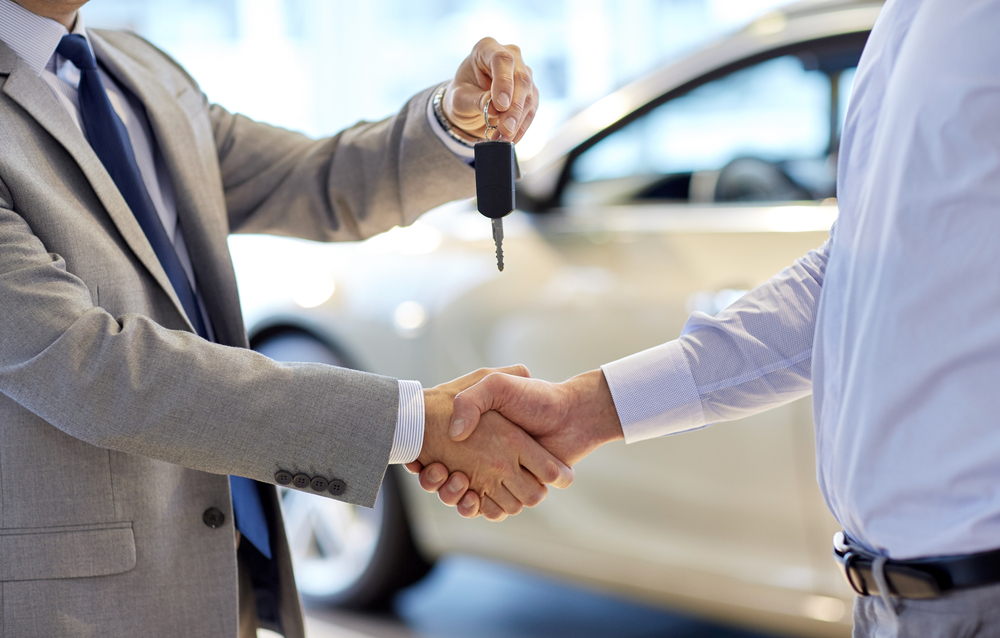 two men shake hands and one is giving the other car key