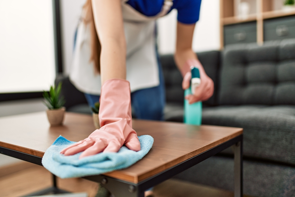 a girl wiping a table with a towel.