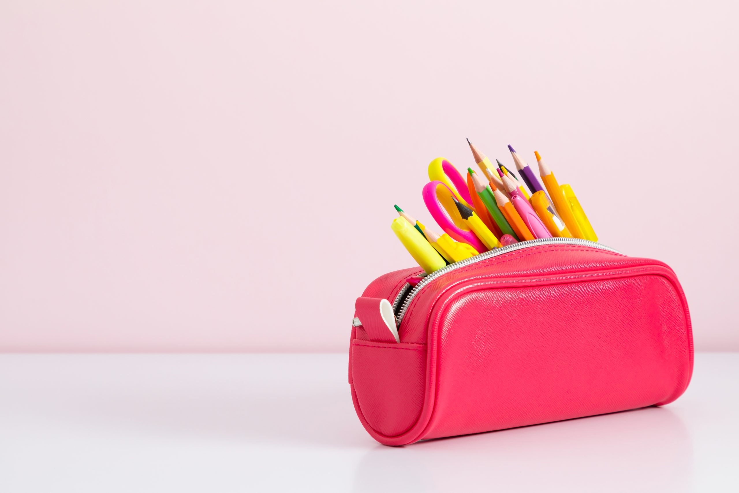 A Pink pencil case with lots of pencils.