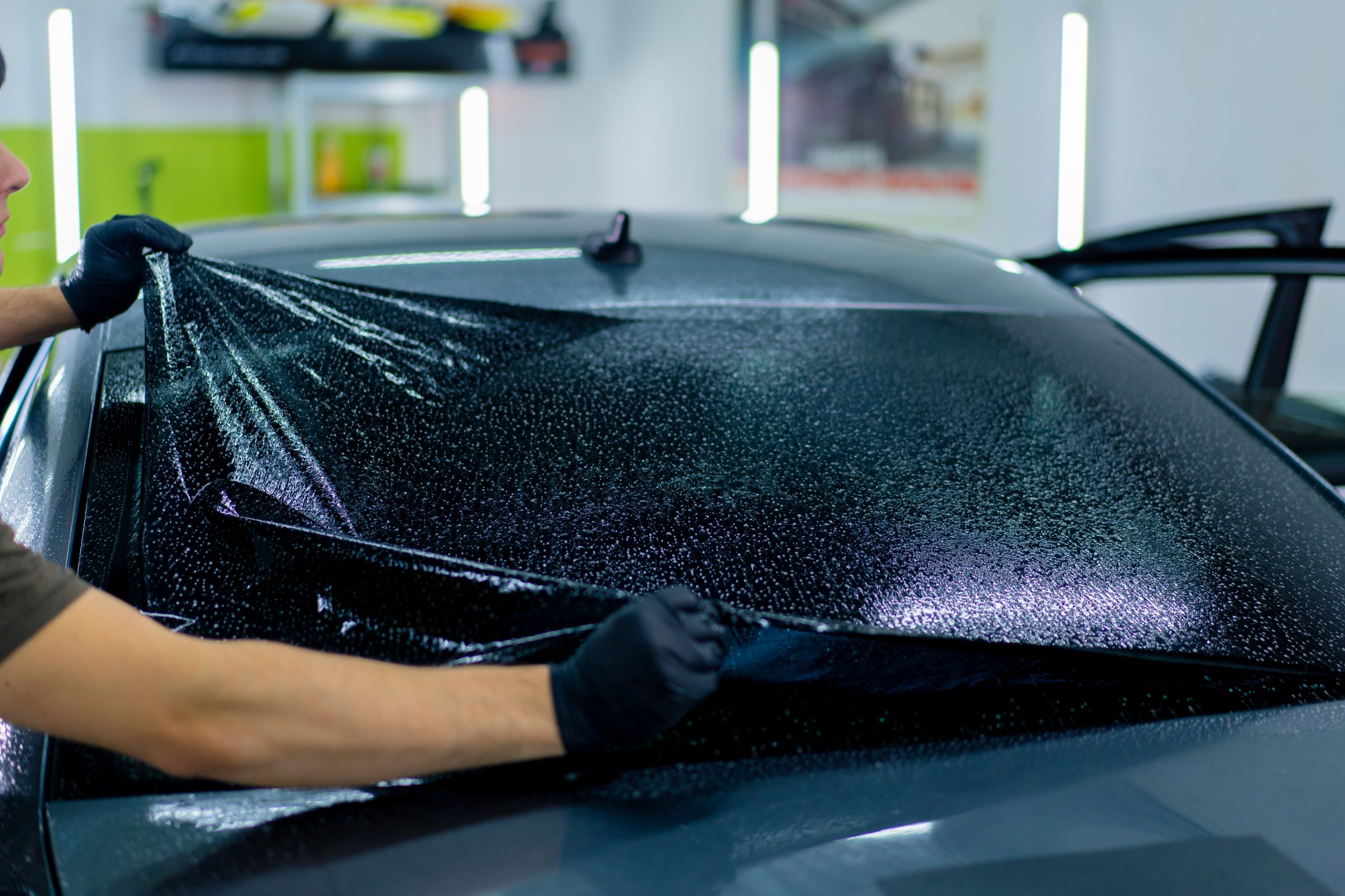 a close up for a worker tinting a rear window for a car
