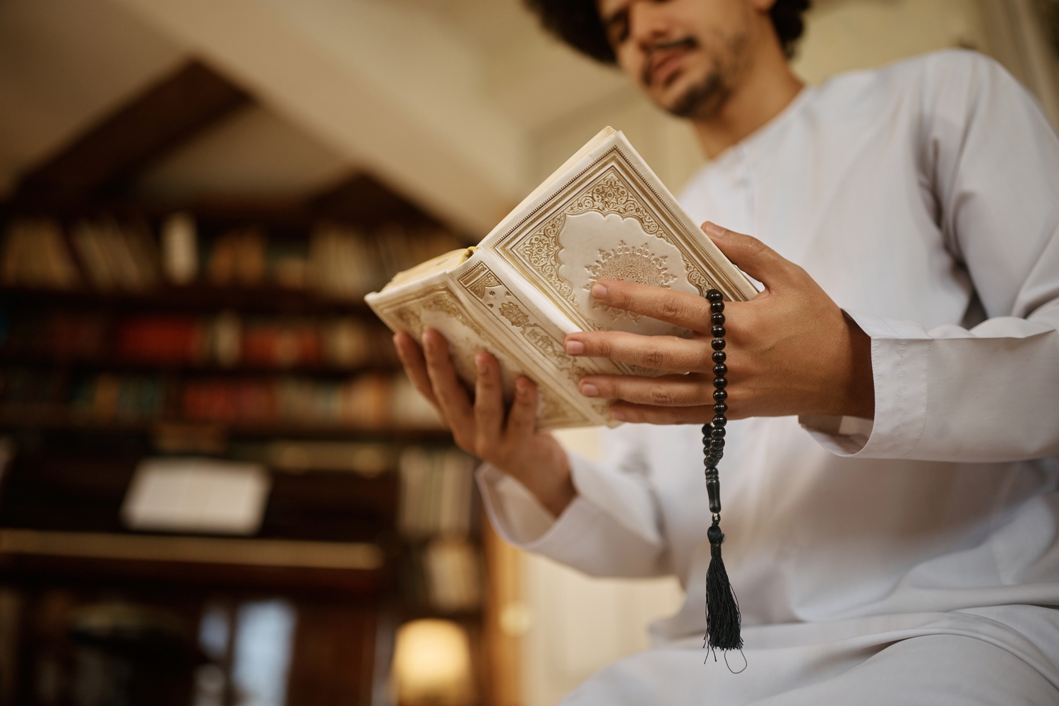 رجل يرتدي مسبحة ويتلو من القرآن الكريم.