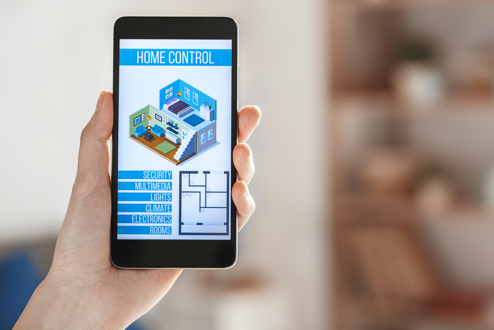 Hand holding an interface of smart home technology application.