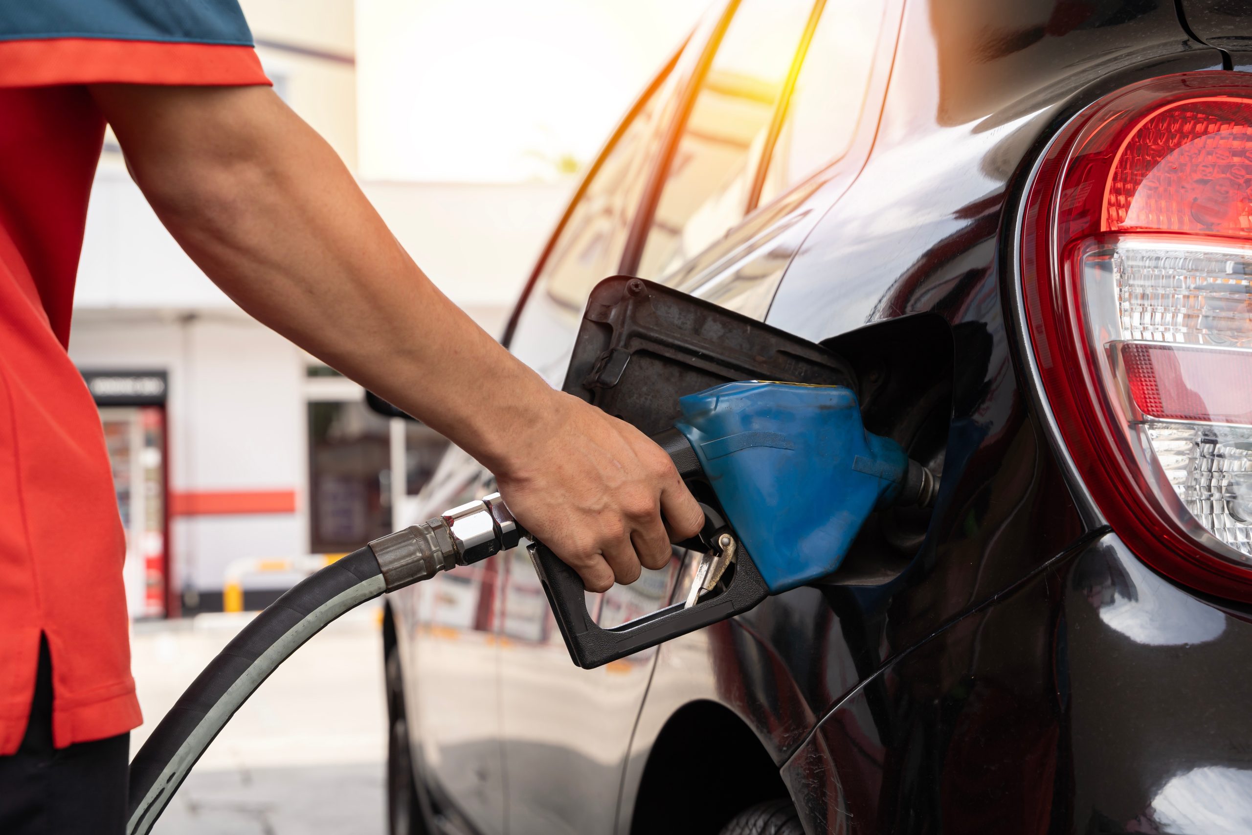 Close up cropped shot of a gas station worker's hands with filling gun, ready to refueling the car with gas or petrol at a gas station.